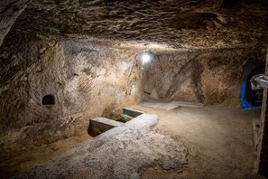 En grotta med en bänk av sten, en liten alkov och en ljuskälla.
