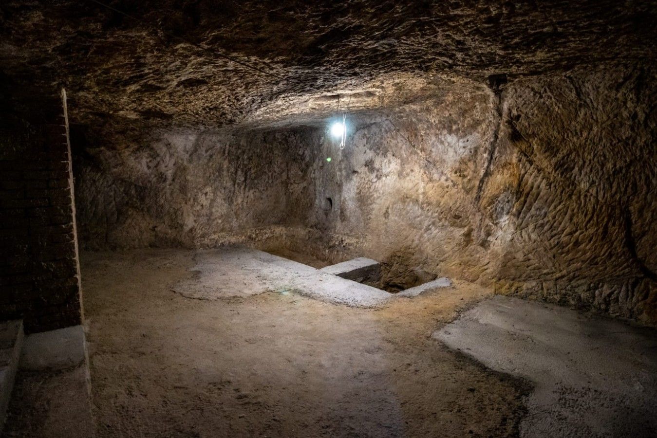 A cave-like interior with rough walls, a light source, and a central stone structure.