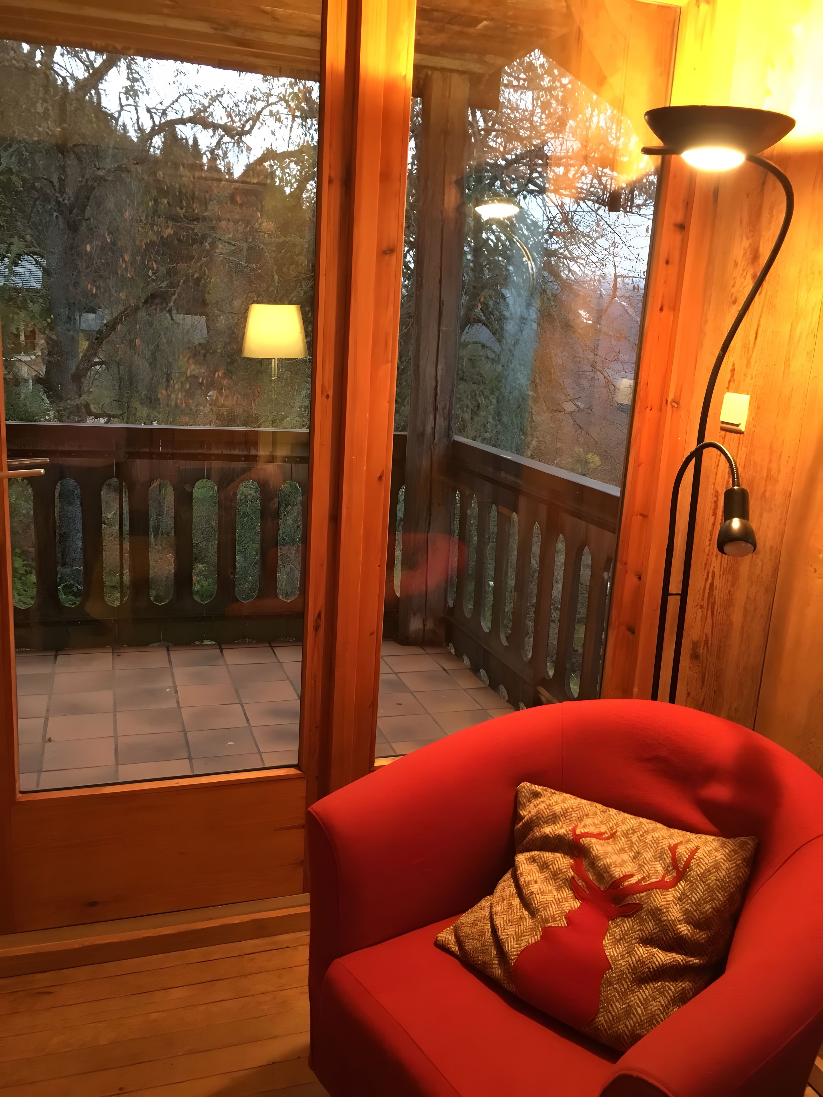 A wooden deck with a red chair and a lamp.