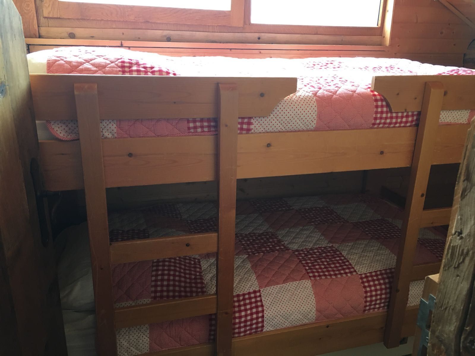 Een stapelbed met een gewatteerde matras en een onderkast met een bedspread met een patroon.