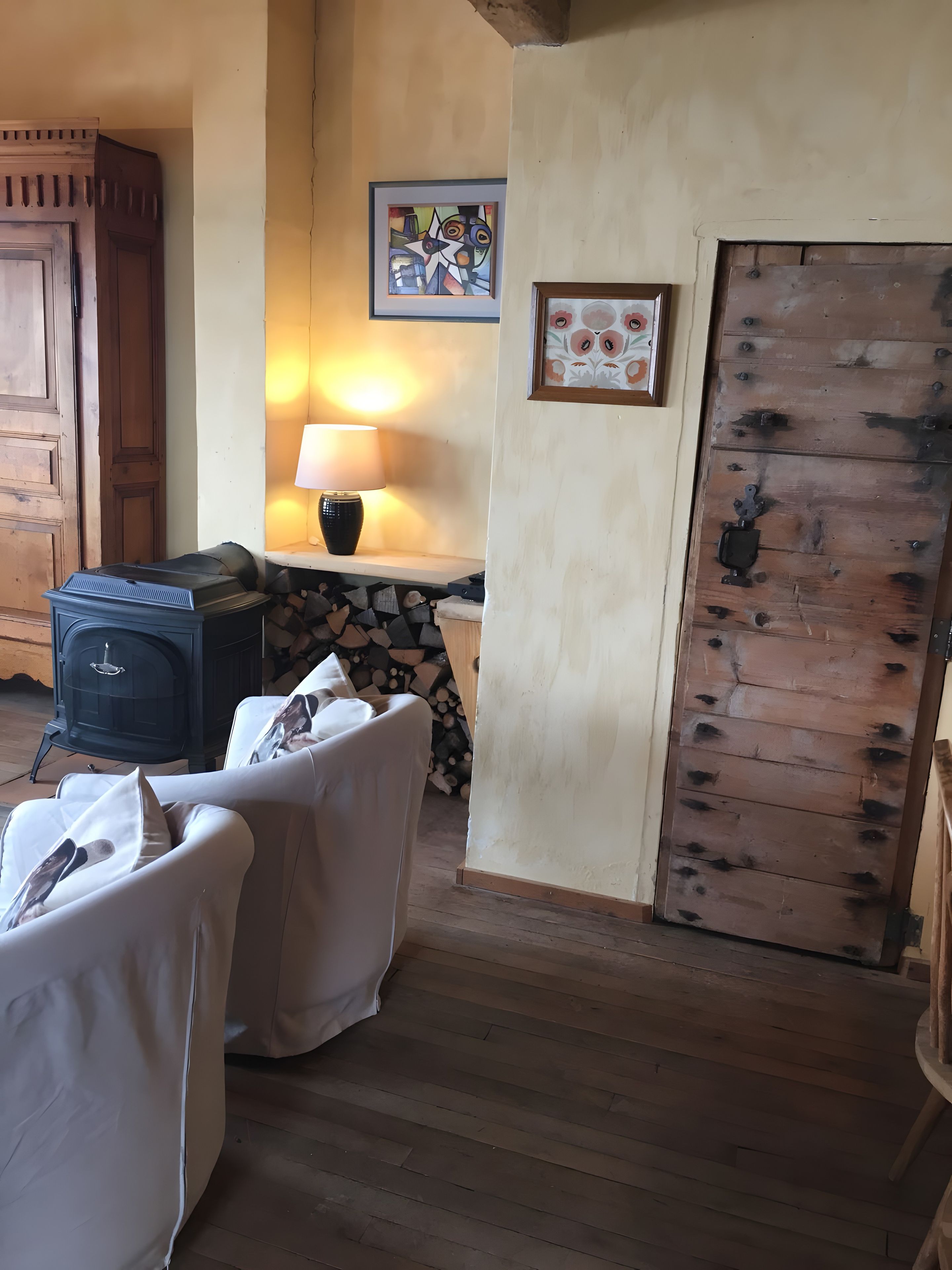Een gezellige kamer met een open haard, een tafel met stoelen en een houten deur.