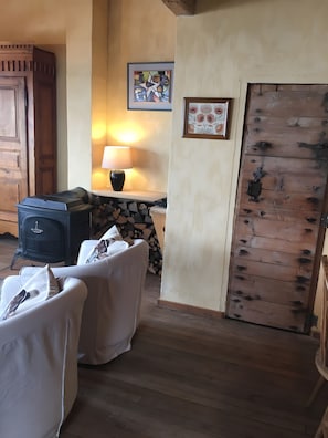 Une pièce chaleureuse avec une cheminée, une table entourée de chaises et une porte en bois.