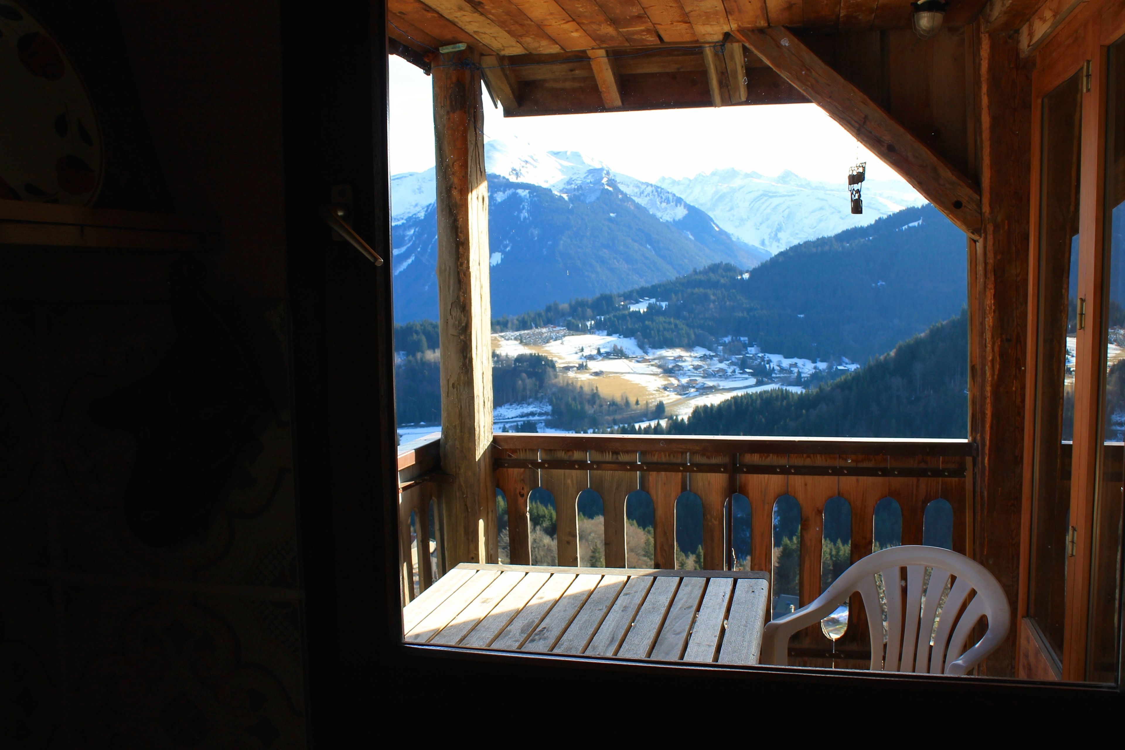 Un balcon en bois offrant une vue sur des montagnes enneigées.