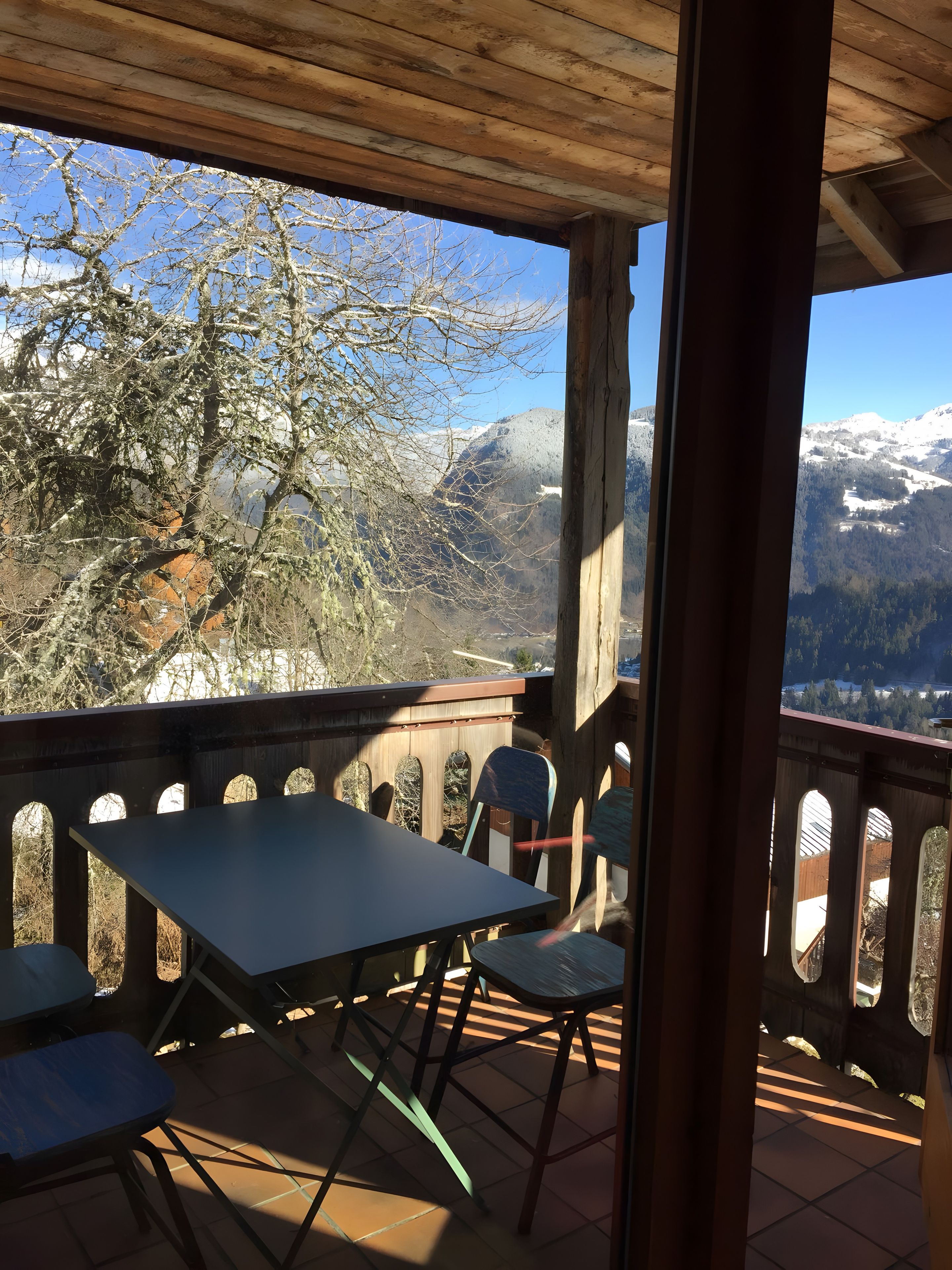 Un espace extérieur abrité, avec une table et des chaises, offrant une vue sur un paysage montagneux.