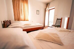 A hotel room with two beds, a window with curtains, a chair, and a door leading outside. - Polgár Elixír Hotel  (Villány)