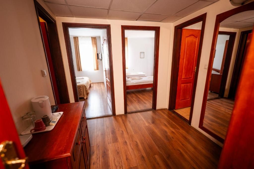 Corredor de hotel com piso de madeira, balcão de recepção e portas que dão para os quartos de hóspedes.