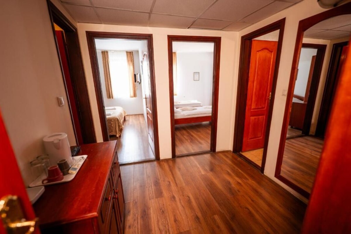 A hotel hallway with wooden flooring, a reception desk, and doors leading to guest rooms.