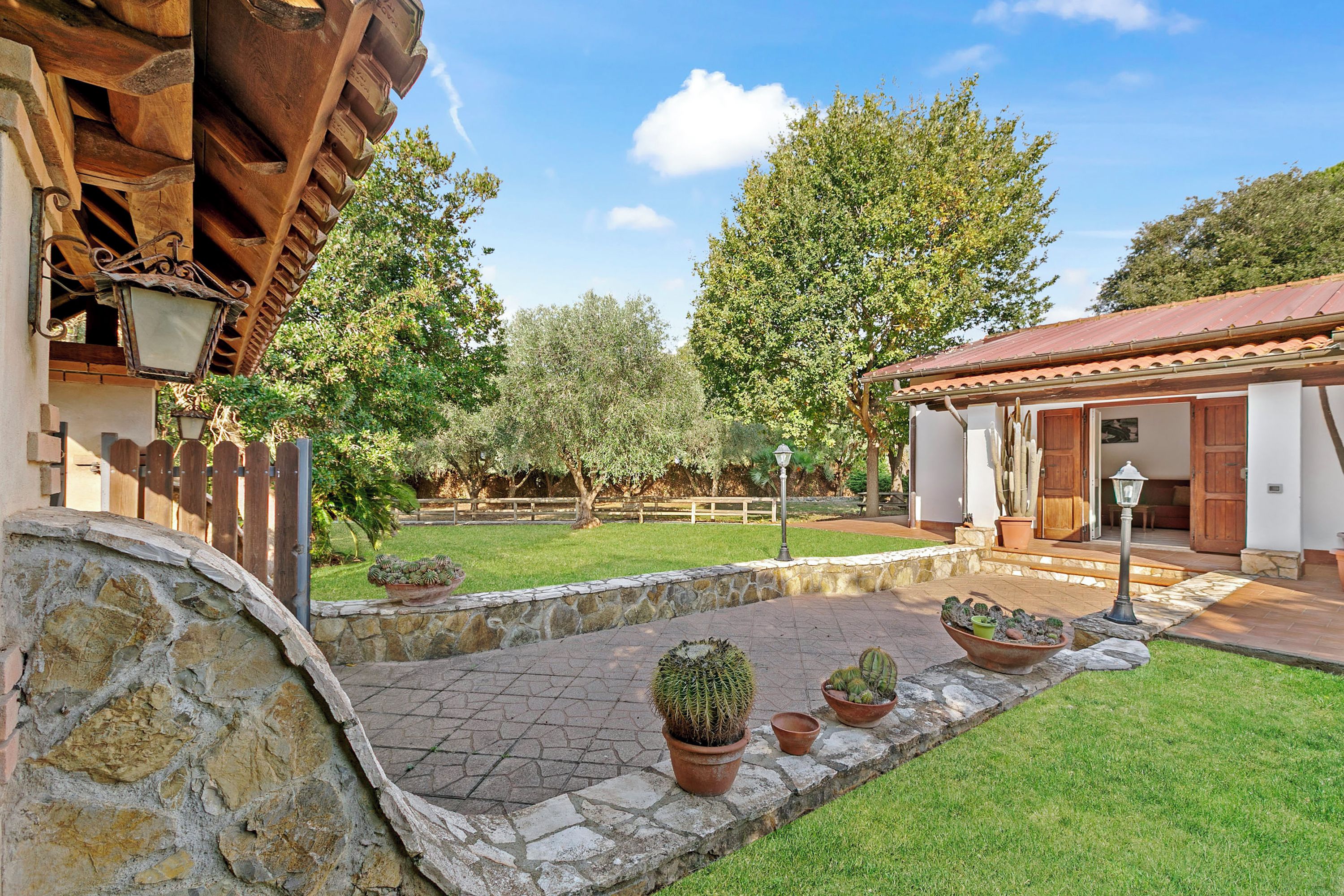 A courtyard with stone walls, potted cacti, and a wooden pergola.