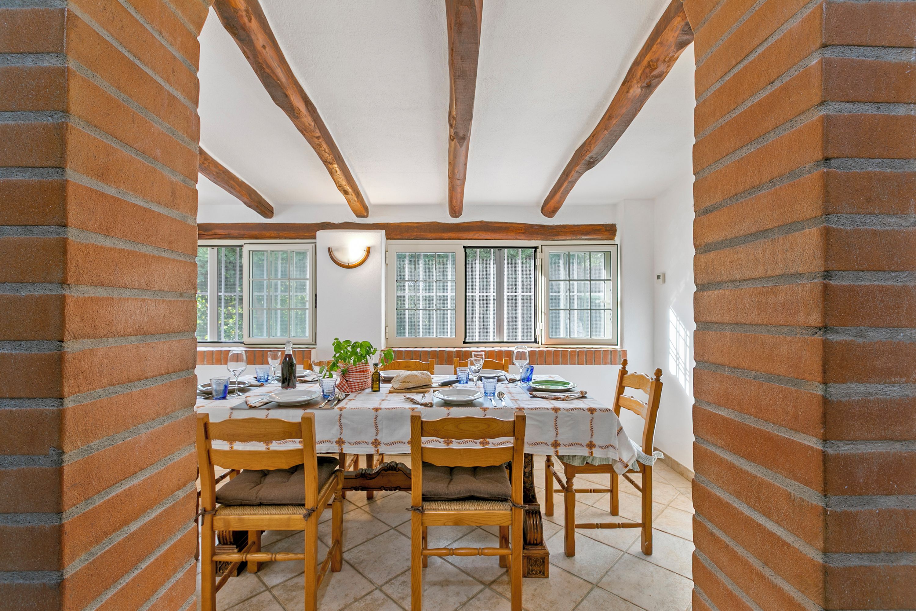 A dining area with a brick wall, wooden beams, and a table set for four.