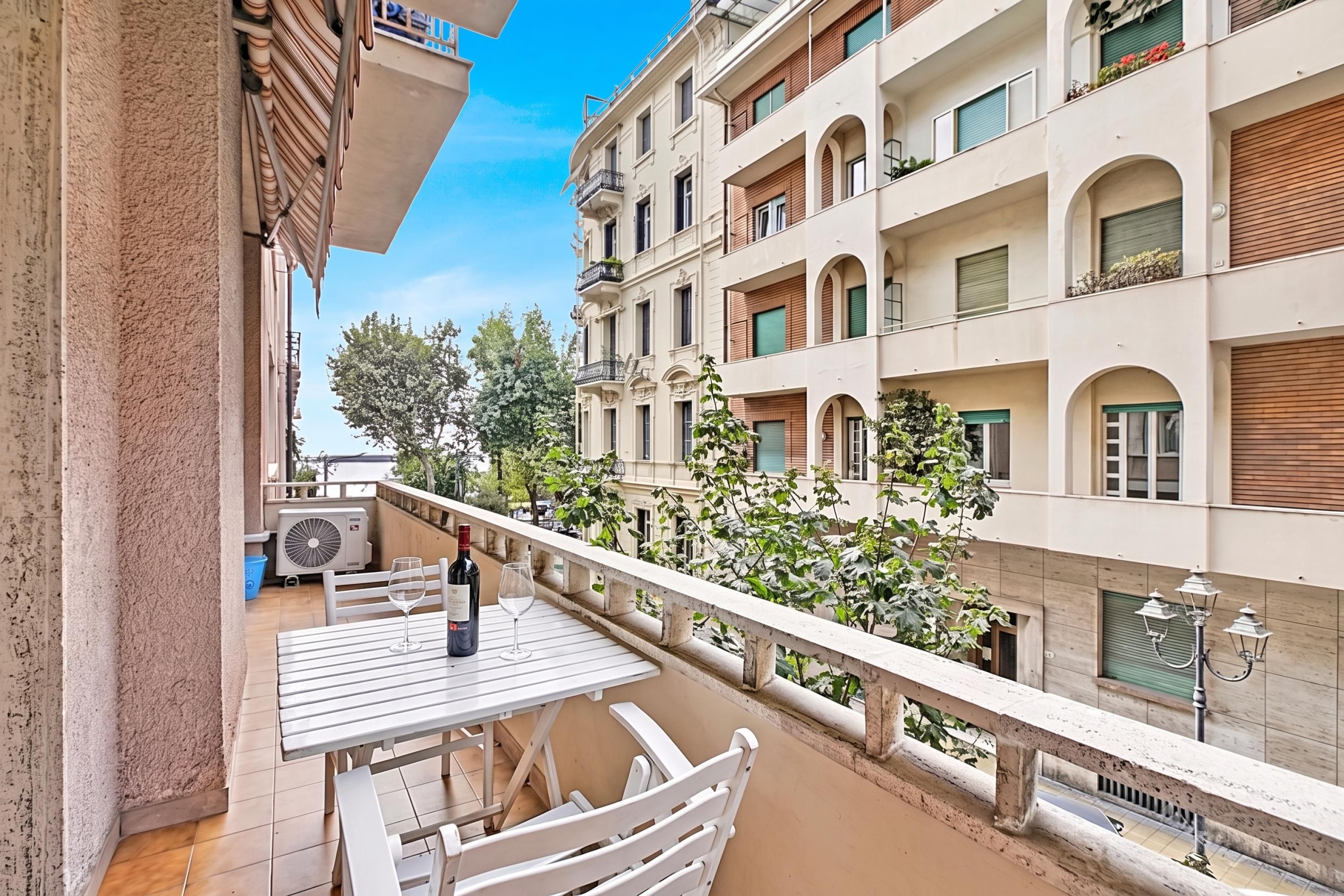 A balcony with a table, chairs, a wine bottle, and a glass.