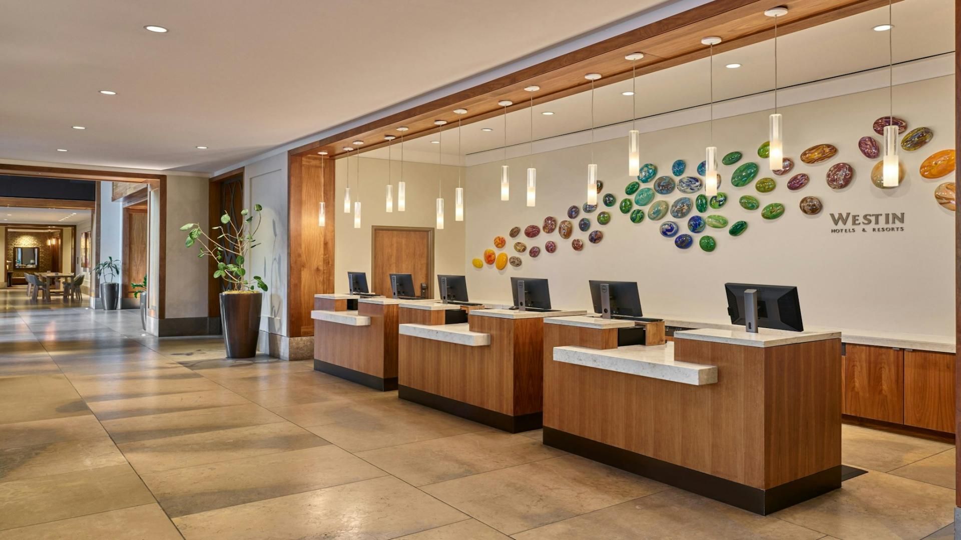 Zona de recepción con mostradores de madera, una pared decorativa de piedras de colores y un letrero de Westin Hotels & Resorts.