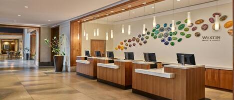 Zona de recepción con mostradores de madera, una pared decorativa de piedras de colores y un letrero de Westin Hotels & Resorts.