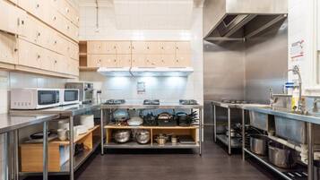 A commercial kitchen with stainless steel appliances, wooden cabinets, and metal shelving.