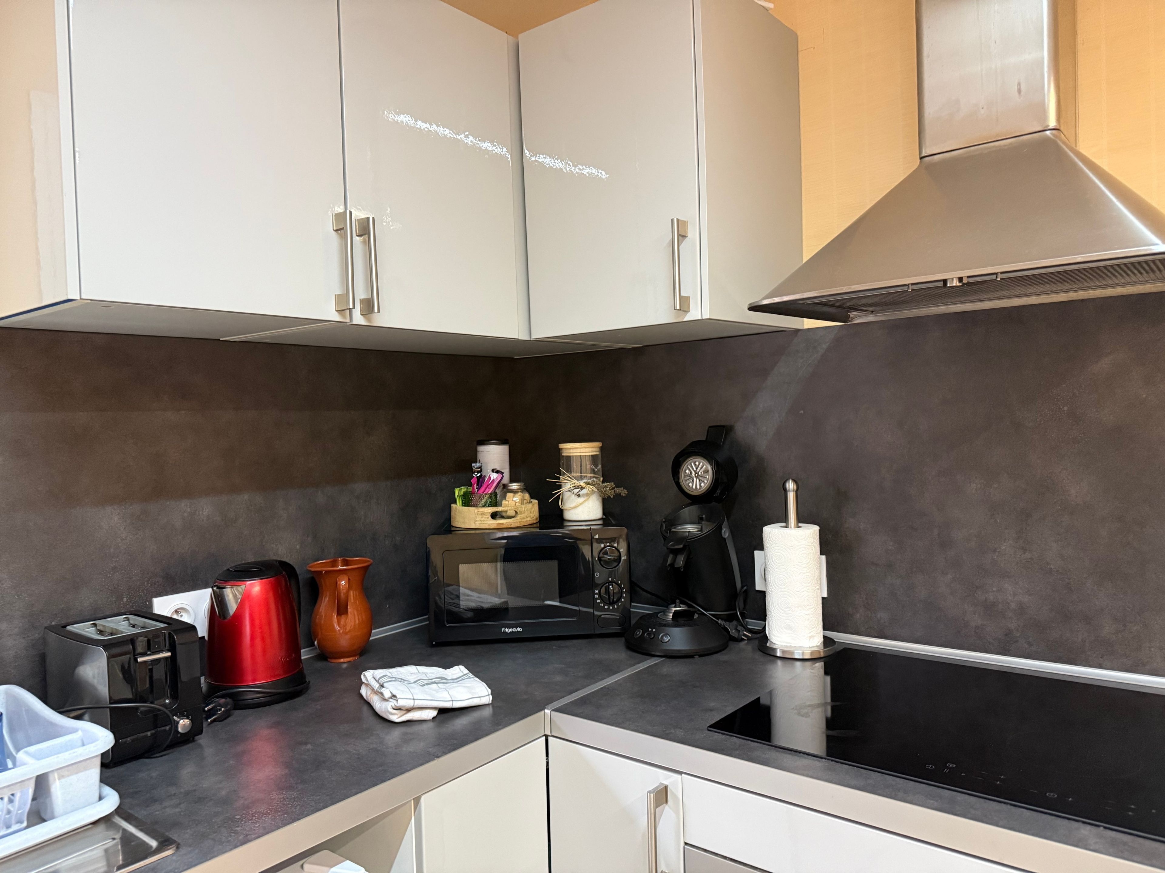Una cocina moderna con armarios blancos, microondas, cafetera y tostadora.