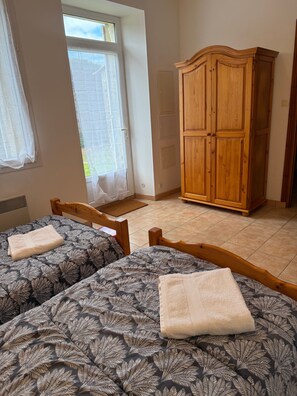 Un dormitorio con dos camas, un armario de madera y una ventana con cortinas.