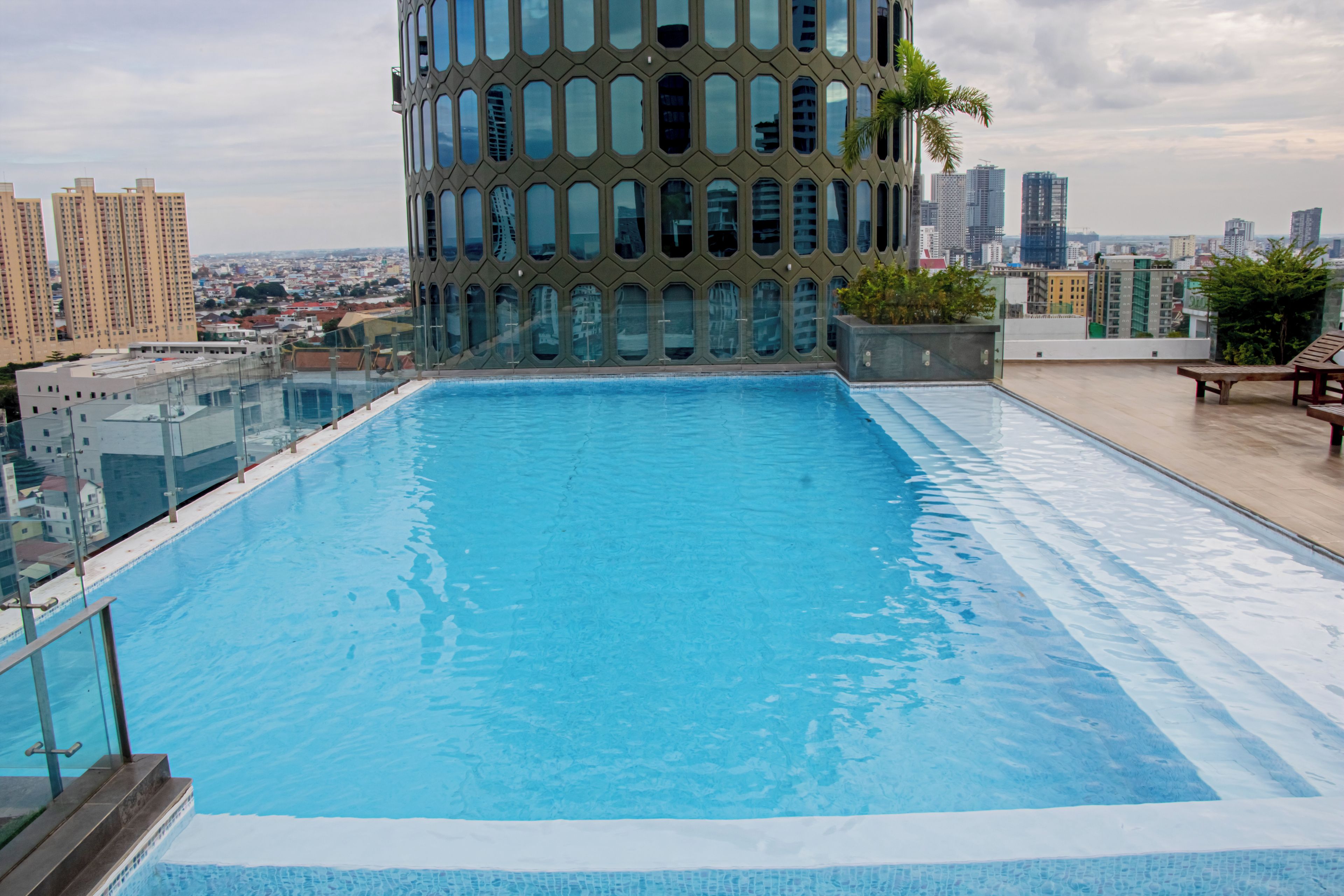 Piscina en la azotea con barandilla de vidrio y vista panorámica de la ciudad.