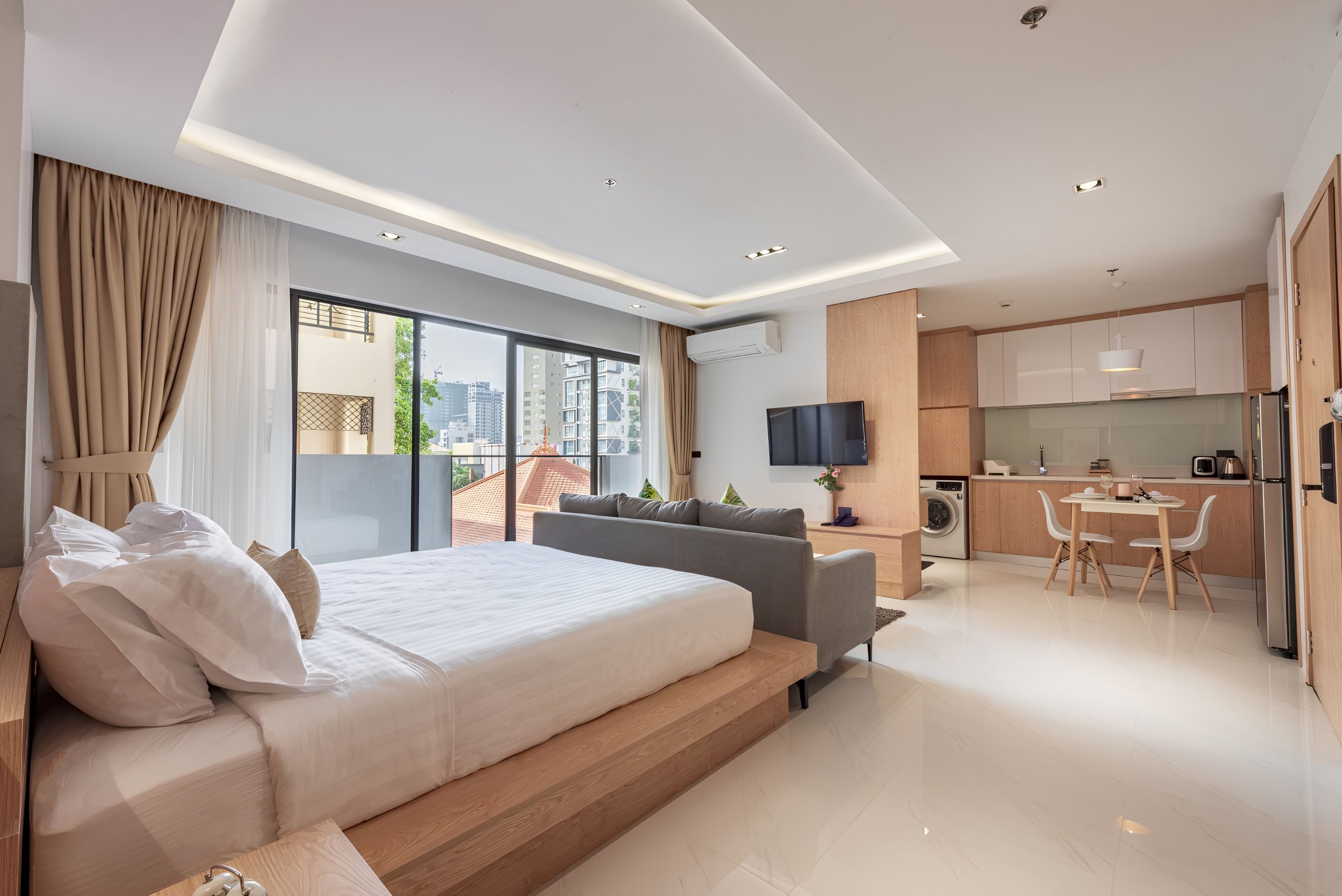 Una habitación de hotel moderna con una cama grande, un sofá, un comedor y una cocina.