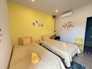 A hotel room with two beds, a yellow wall, and a small desk with a chair. - Good Sleep House (Ban Ta Khun)