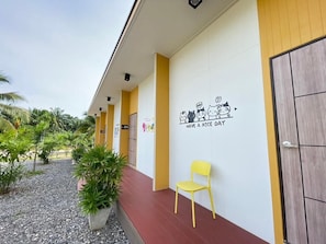 A building exterior with a wall-mounted sign that reads 'HAVE A NICE DAY' and a yellow chair outside. - Good Sleep House (Ban Ta Khun)