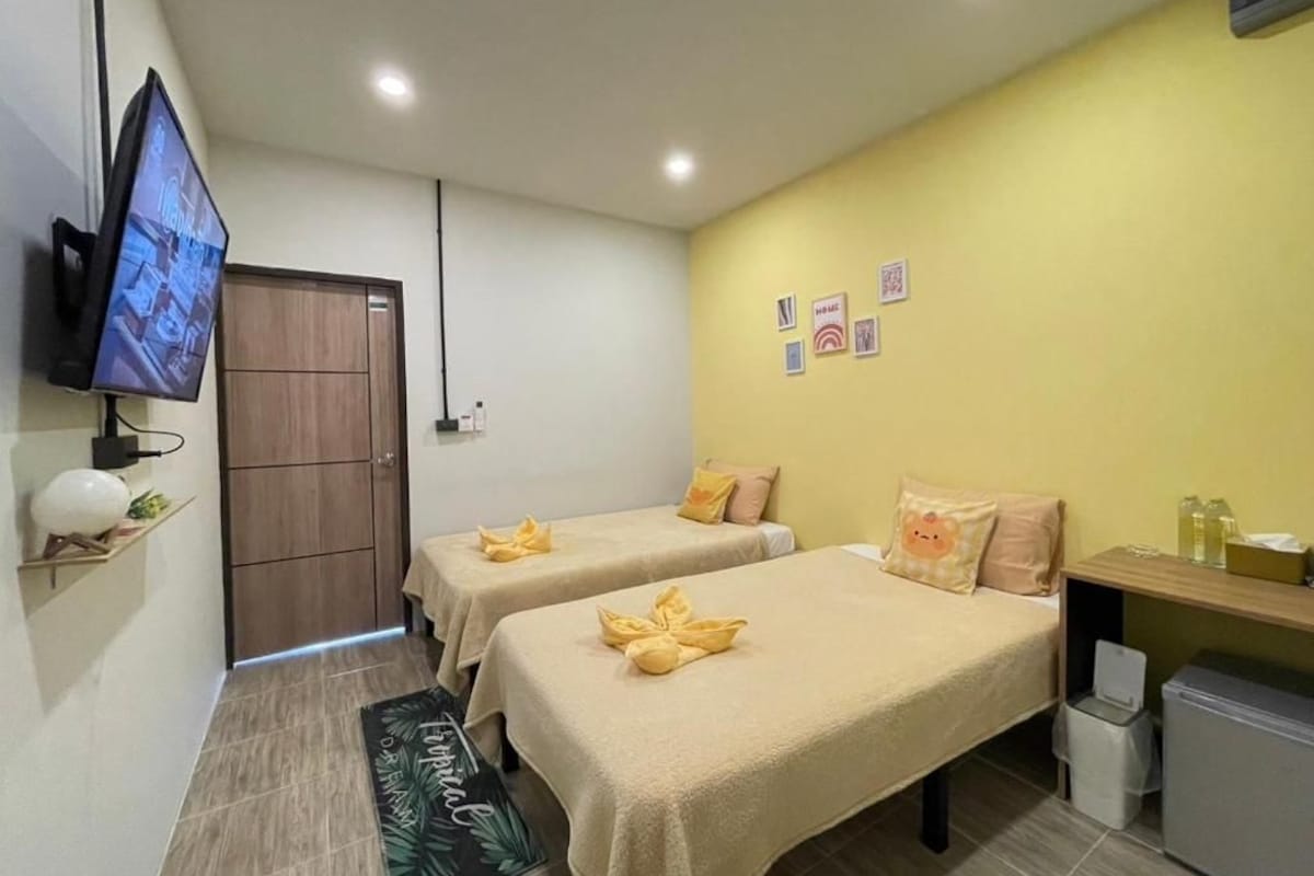 A hotel room with two beds, a television, a small desk, and a trash bin.
