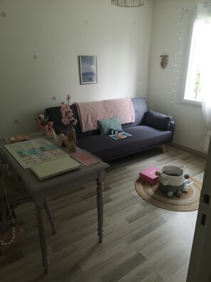 A living room with a sofa, a table with books and a vase, and a decorative basket on the floor. - New Listing (Leigné-sur-Usseau)