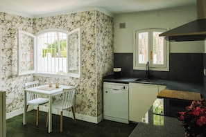 A kitchen with a dining area, featuring a white table, chairs, and a Bosch dishwasher. - New Listing (Alcocéber)
