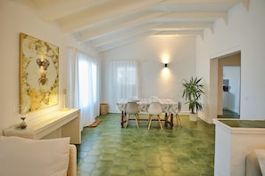 A dining area with a table and chairs, a wall-mounted light fixture, and a potted plant. - New Listing (Alcocéber)