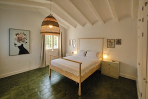 A bedroom with a wooden bed, a hanging light fixture, a window with curtains, and artwork on the walls. - New Listing (Alcocéber)