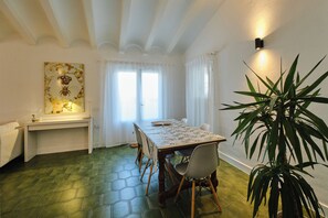 A dining area with a table set for four, a potted plant, and a wall-mounted light fixture.
