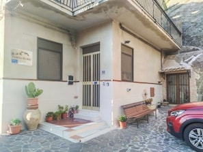 Un edificio con un letrero que dice 'PORTA NORD', una entrada con rejas, un banco y un coche rojo estacionado.