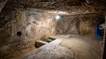 Eine Höhle mit Steinsitzbank, einer kleinen Nische und einer Lichtquelle.