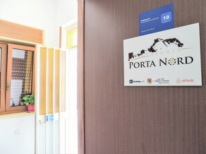 Un letrero que dice 'Rifugio Porta Nord' con logotipos de Booking.com, Airbnb y un código de un consejo local.