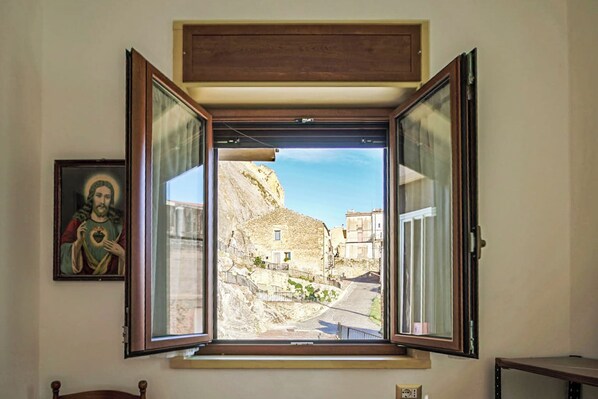 Una habitación con ventana que da a la calle, un cuadro en la pared y un enchufe.