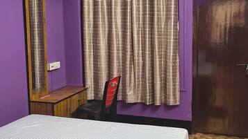 A room with a bed, a chair, a mirror, and a door.