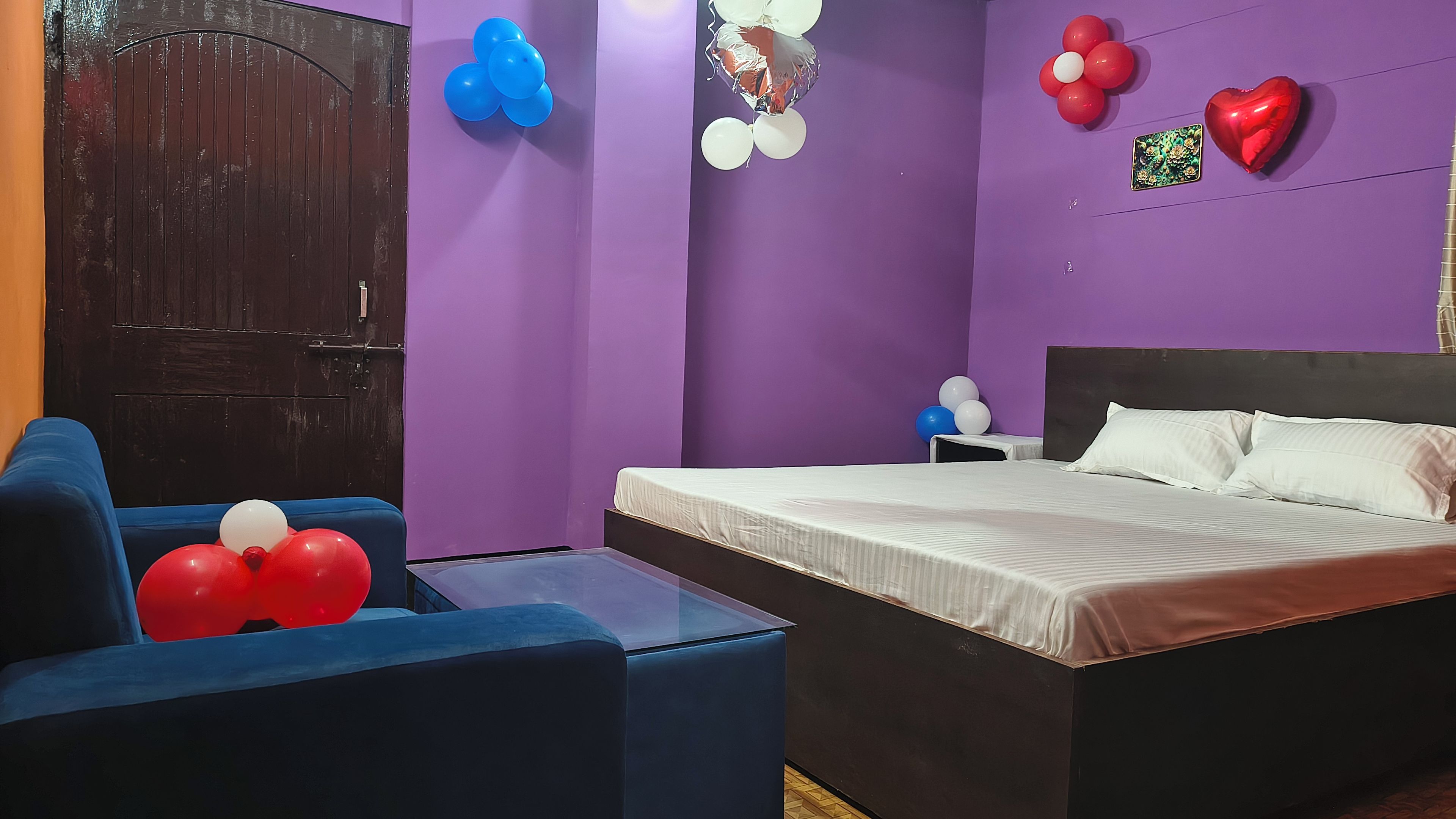 A room with a bed, a blue armchair, and balloons on the walls.