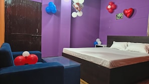 A room with a bed, a blue armchair, and balloons on the walls. - jr hotel  (Guwahati)