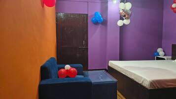 A room with a bed, a blue armchair, a small table, and purple walls.