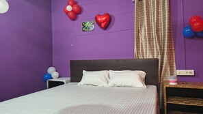 A room with a bed, a nightstand, and a wall with balloons. - jr hotel  (Guwahati)