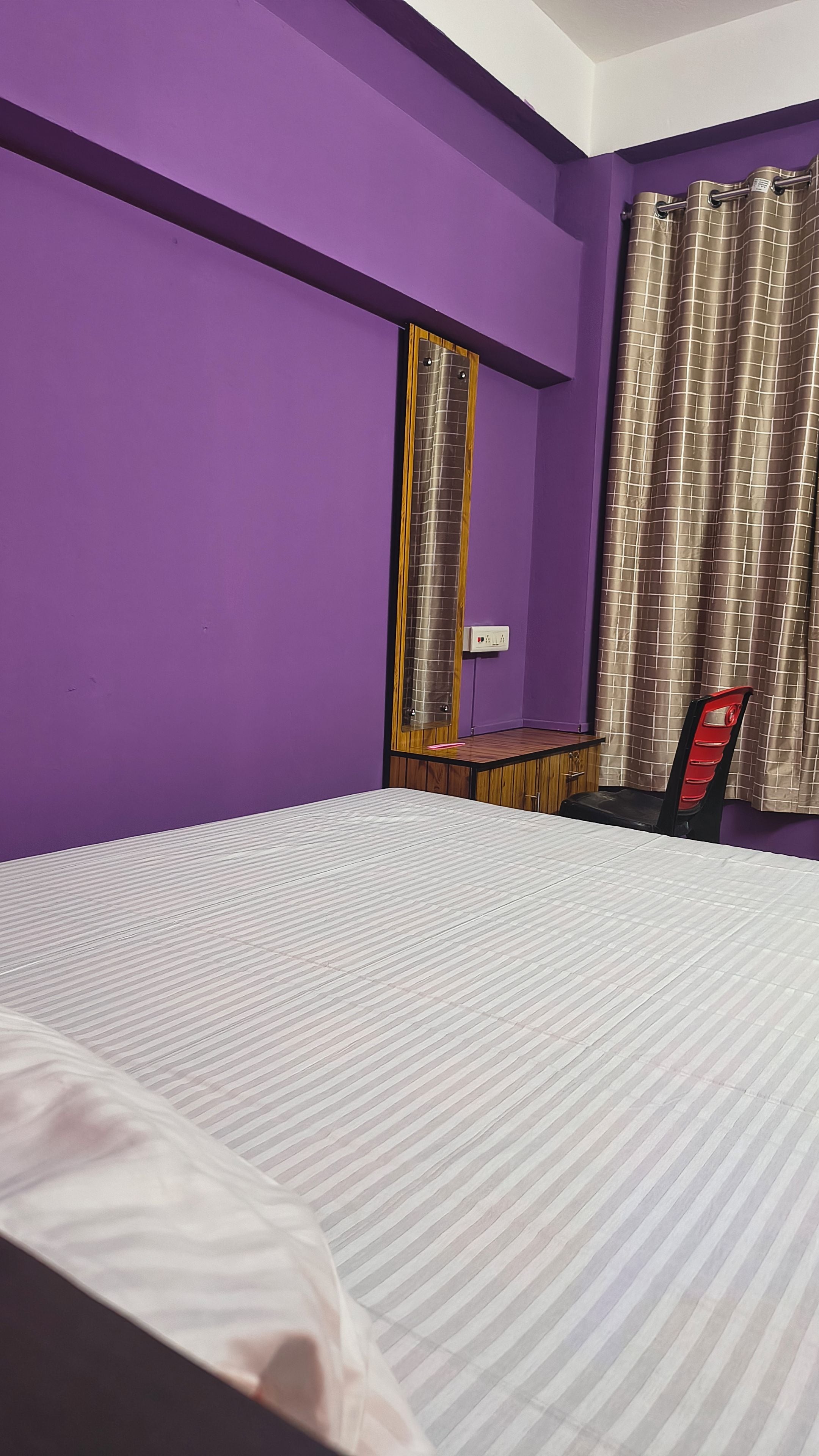 A room with a bed, a desk, a chair, and a window with curtains.