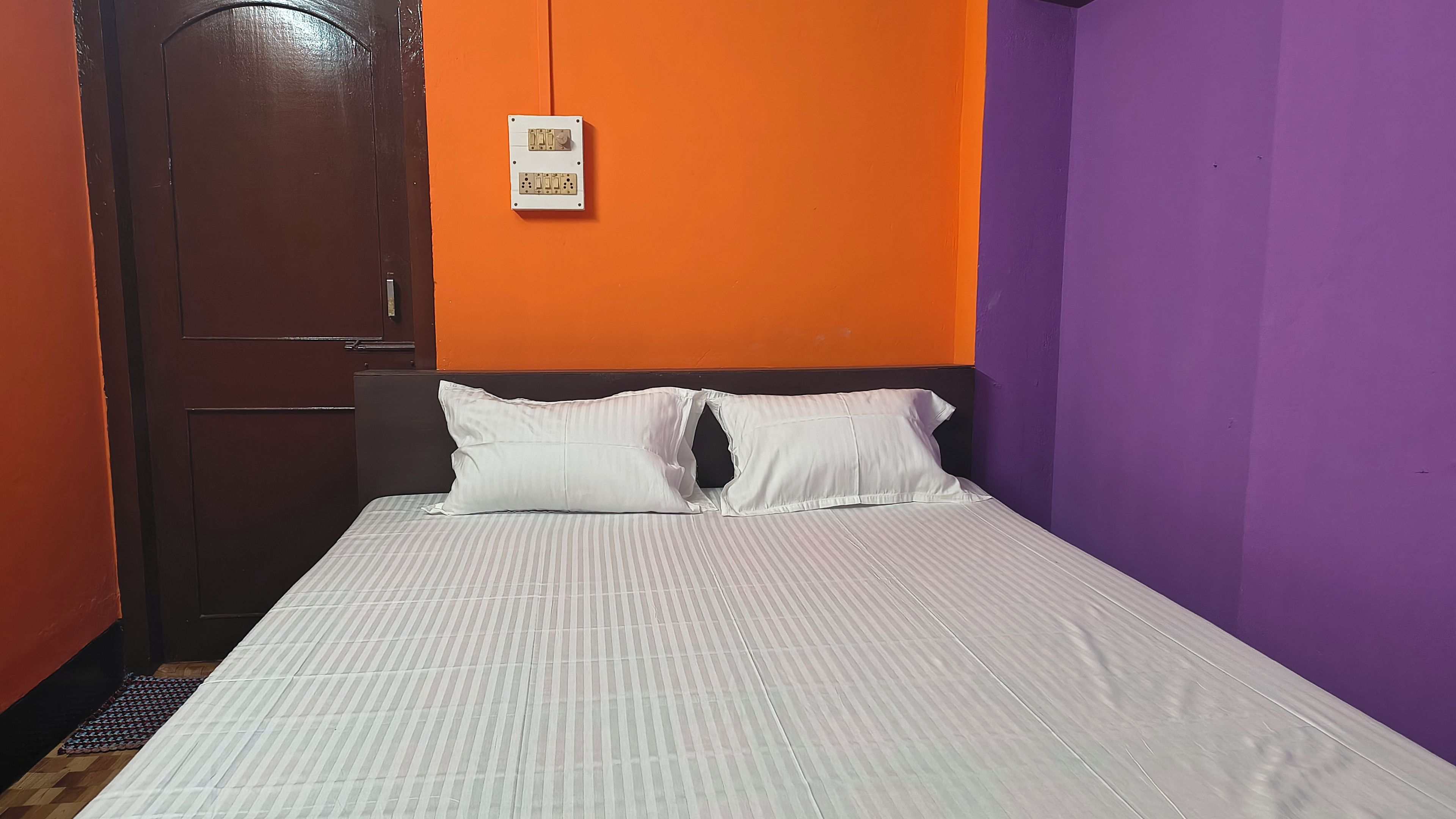 A room with a bed, a door, and a wall socket.