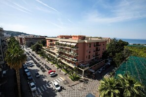 A multi-story hotel with balconies, a parking lot, and a view of the sea. - Sea Room Sorrento (Sorrento)