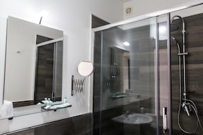 A modern bathroom with a glass-enclosed shower, a round mirror, and a vanity with a glass countertop. - Sea Room Sorrento (Sorrento)