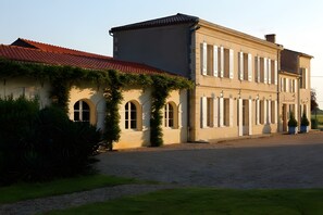 A building with a red-tiled roof, arched windows, and a paved driveway. - Country House 'Domaine Rollan De By' with Private Terrace, Wi-Fi and Air Conditioning (Bégadan)