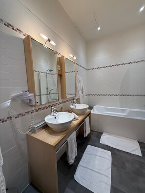 Ein modernes Badezimmer mit zwei Waschbecken, einer Badewanne, einem Spiegel und einem Fön.