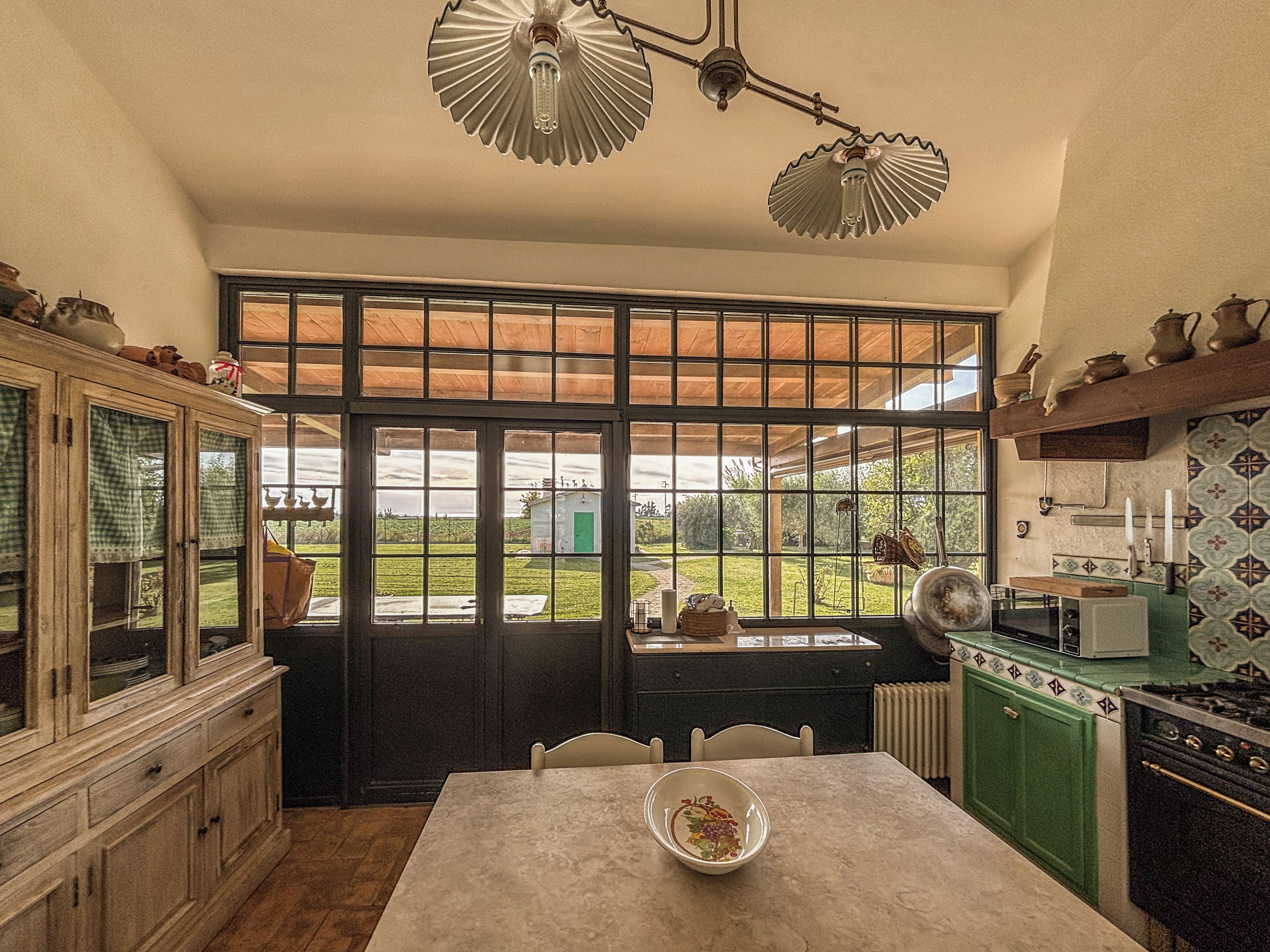 Una cocina con un ventanal grande, armarios de madera, una mesa con un cuenco y una estufa.