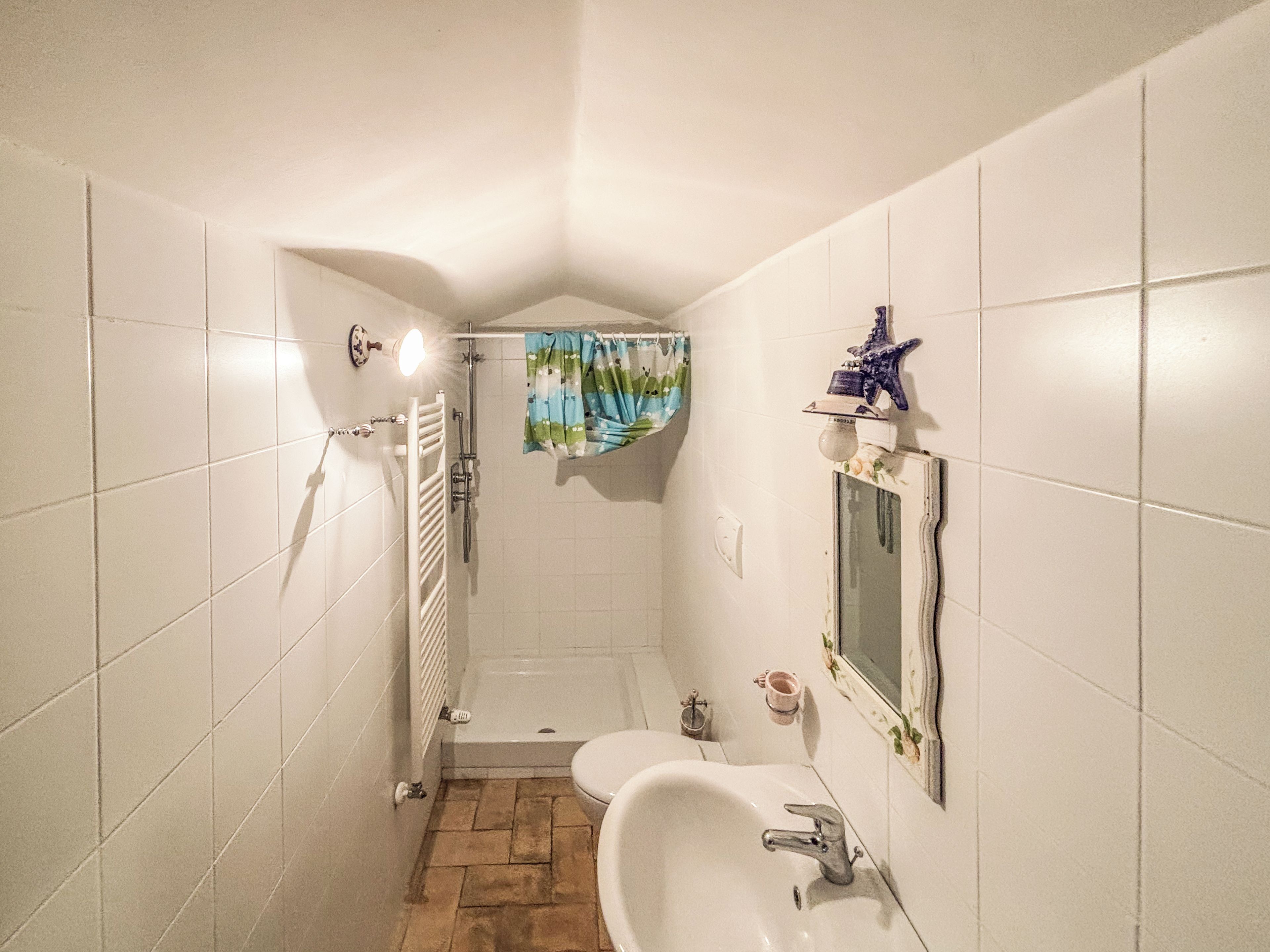 Et badeværelse med badekar, bruser og toilet.