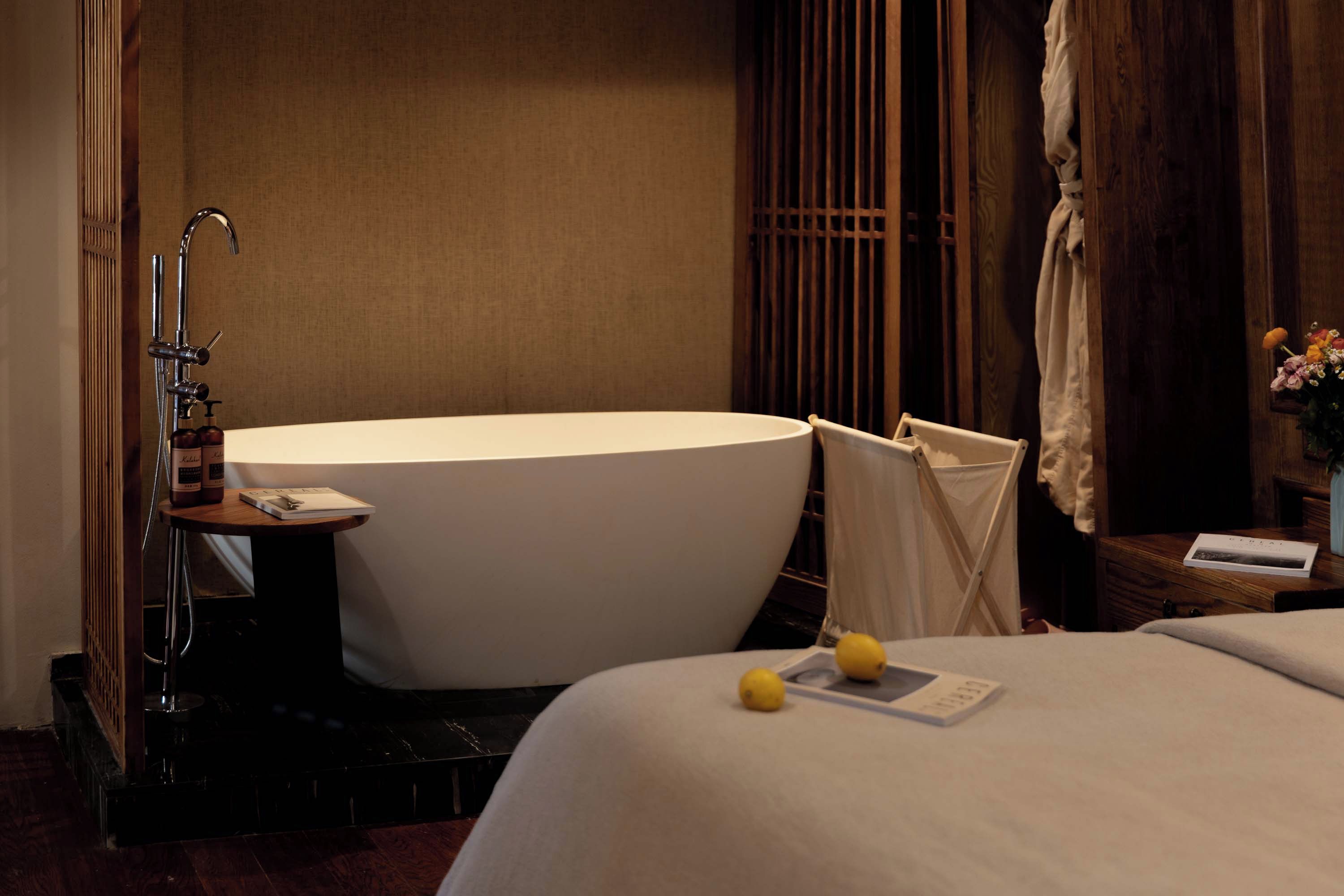 A modern bathroom with a freestanding bathtub, a small table with a book, and a towel rack.