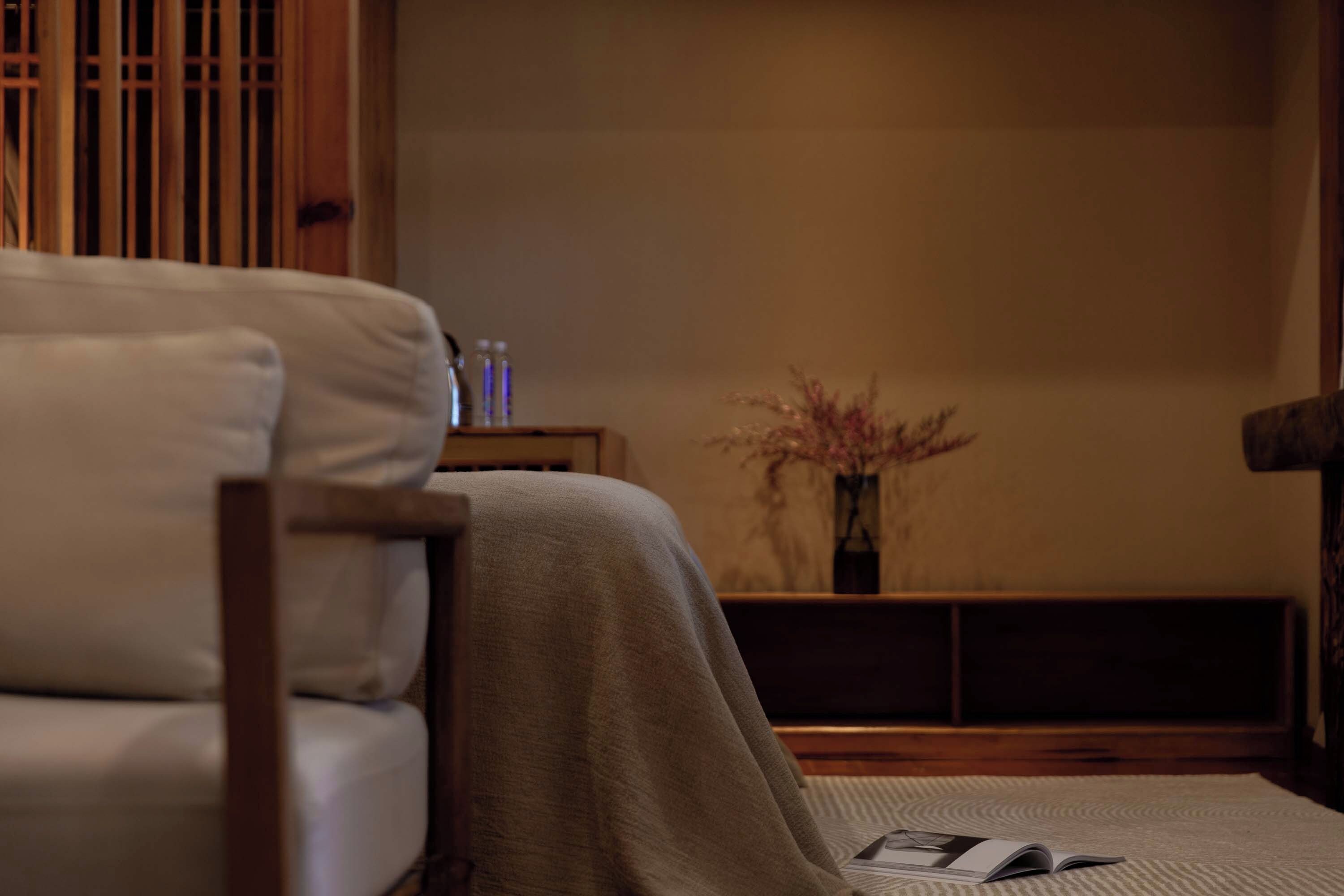 A room with a sofa, a small table with a vase, and a magazine on the floor.