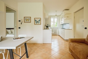 Una cocina moderna con armarios blancos, una mesa de comedor y un sofá. Hay dos cuadros de mariposas en la pared.