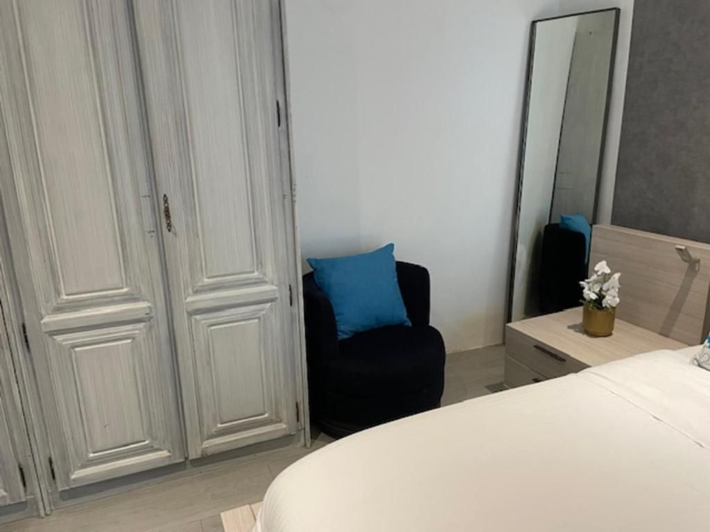 Un dormitorio con cama, una silla, una mesita de noche, un espejo y un armario.